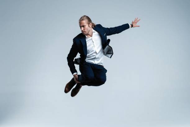 istock Young successful businessman in suit rejoicing, jumping over white background. 1077171010