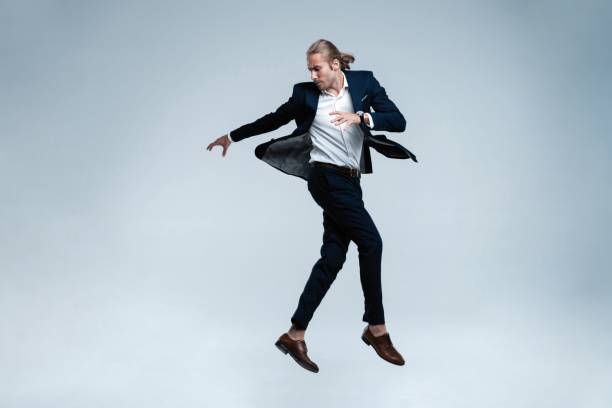 istock Young successful businessman in suit rejoicing, jumping over white background. 1077171026