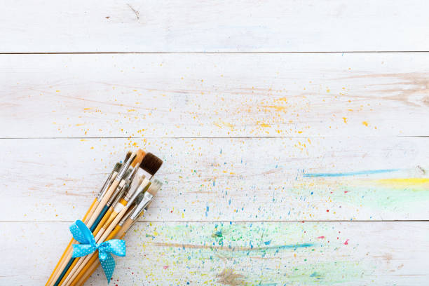 istock Paint brushes set on white wooden painted stained table with splashes, artistic canvas background, creative space for painting, painter workplace, children kids art desk, top view with copy space 1077171322