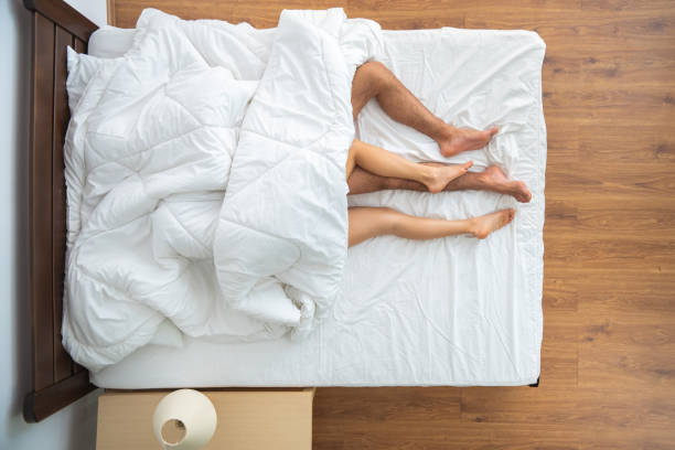布団の下のカップルはベッドの上に横たわっていました。上から見る - bed couple human foot heterosexual couple ストックフォトと画像