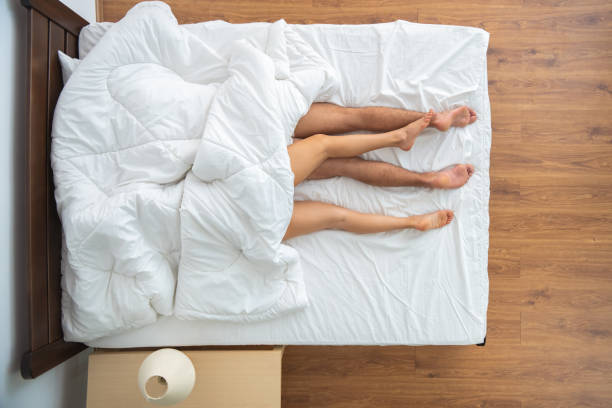 毛布の下の男と女がベッドに横たわっていた。上から見る - bed couple human foot heterosexual couple ストックフォトと画像