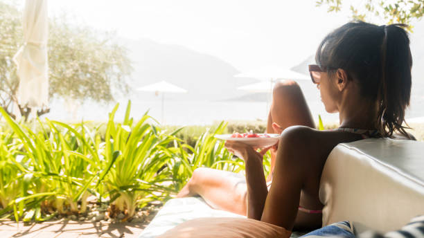 istock Beautiful Woman eating a fruit salad on the beach 1077175656