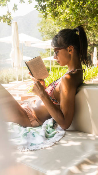 istock Woman reading book, enjoying sun on beach 1077175664