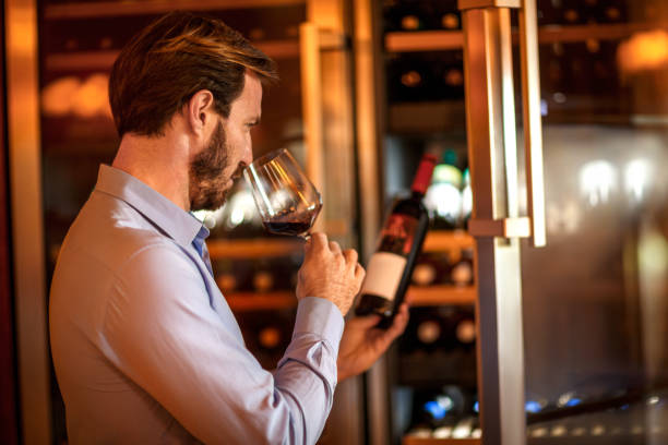 istock Man tasting and degustating wine in front of a wine cooler 1077179060