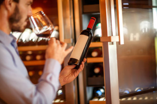 istock Man tasting and degustating wine in front of a wine cooler 1077179204