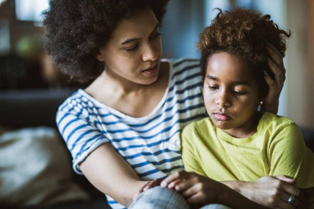 afro americana madre consolando a su muchacha triste en casa. - tristeza fotografías e imágenes de stock
