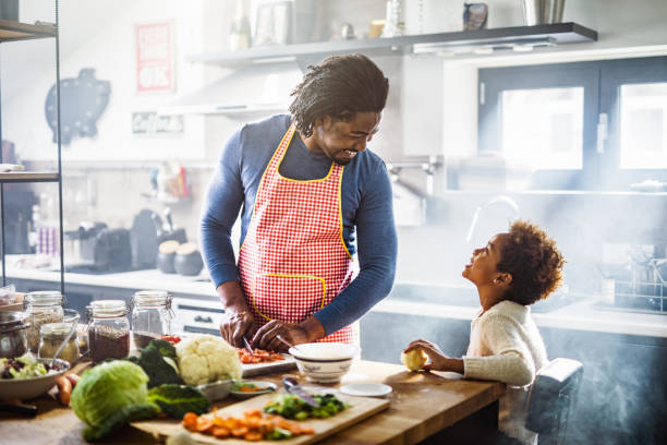 istock Happy black father talking to his daughter while making lunch in the kitchen. 1077179750