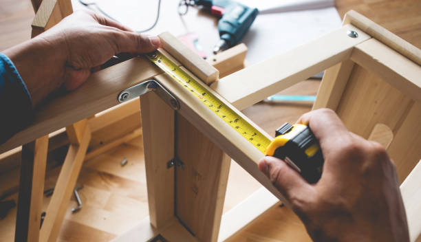 Man assembly wooden furniture,fixing or repairing house with tape measures Man assembly wooden furniture,fixing or repairing house with yellow tape measures. adjusting seat stock pictures, royalty-free photos & images