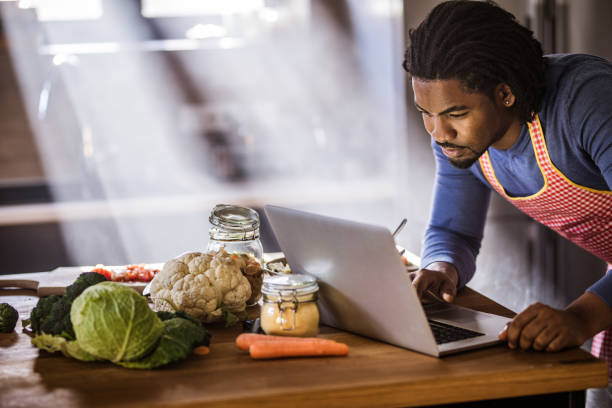 istock African American bachelor searching recipes over Internet in the kitchen. 1077180450