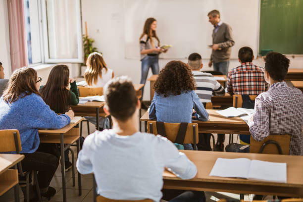 istock Rear view of large group of students attending a class at high school. 1077182324
