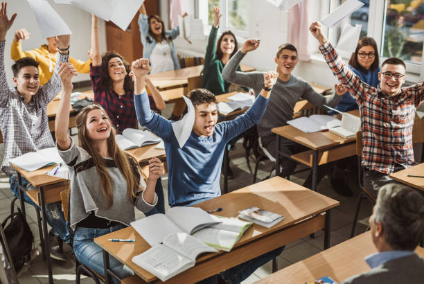 Young couple of students, a guy and a girl, sit at a desk at a lecture and hold hands
