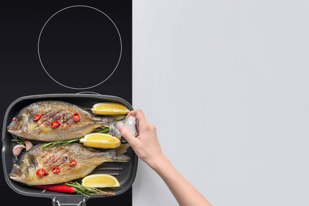 istock cropped shop of person adding salt while cooking fish on grill 1077190836