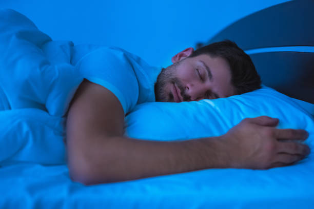 The man sleeping on the bed. evening night time stock photo