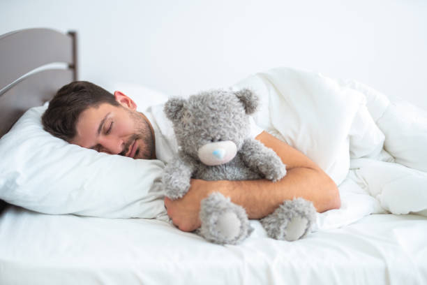 istock The man sleeping with a soft toy on the white background 1077191288