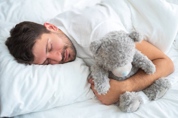 istock The man sleeping with a soft toy on the white background 1077191382