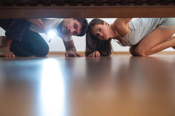istock The man and a woman with a flashlight looking under the bed 1077193898