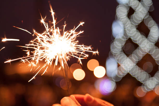 istock Bengal fire in man hands on Christmas tree lights background 1077203240