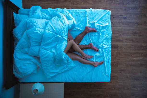 The man and a woman laying under a duvet. evening night time. view from above stock photo