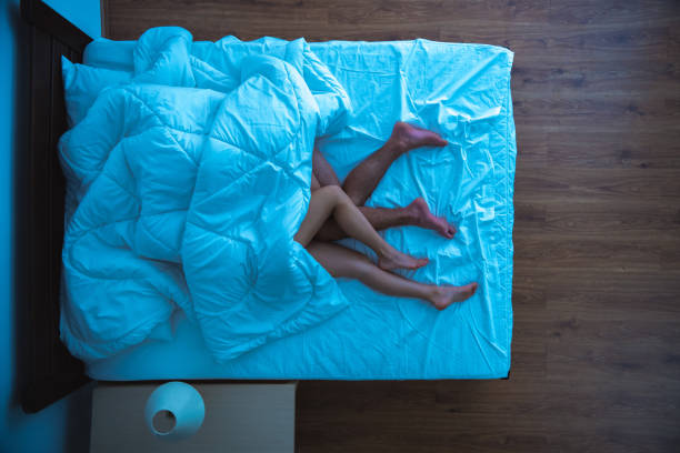 the man and a woman laying under a duvet. evening night time. view from above - sexuality imagens e fotografias de stock