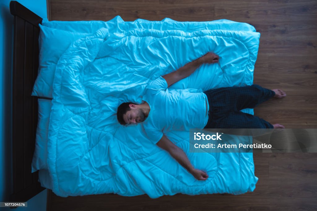 The man laying on the bed. view from above, evening night time Bed - Furniture Stock Photo