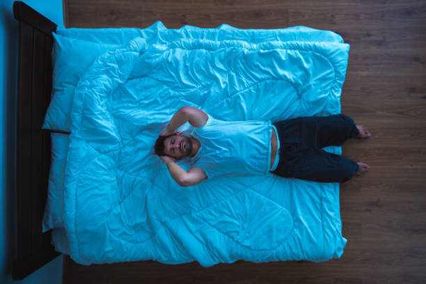 der depressive mensch mit auf dem bett. ansicht von oben, abend, nacht - crane shot stock-fotos und bilder