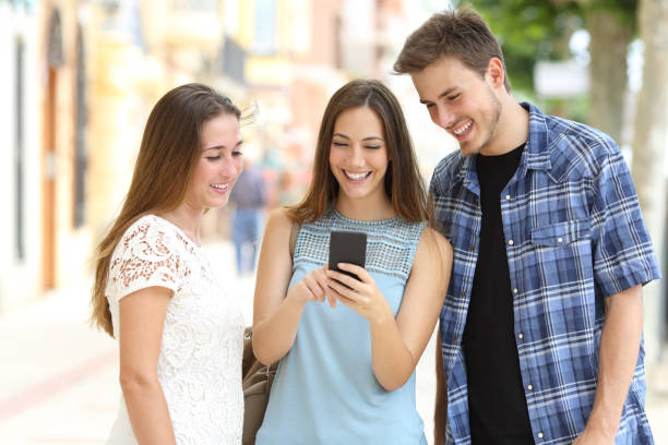 istock Three friends checking smart phone content in a street 1077205664