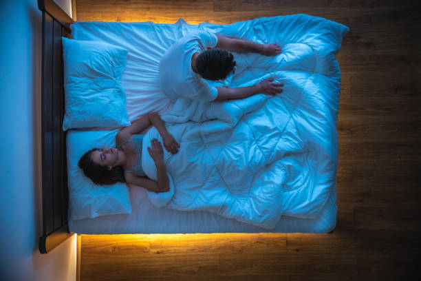The man with an insomnia sitting near a sleeping woman on a bed. view from above The man with an insomnia sitting near a sleeping woman on a bed. view from above horror waking up bed women stock pictures, royalty-free photos & images