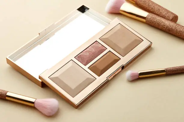 Photo of Make up palette and brushes on beige background