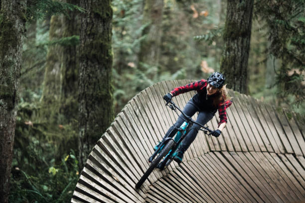 mujer ciclismo de montaña en senderos del bosque - mountain biking extreme sports cycling bicycle fotografías e imágenes de stock