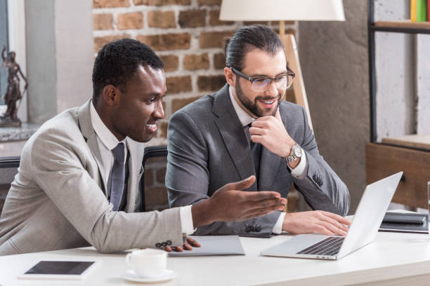 istock multiethnic businessmen smiling and looking at laptop screen in office 1077208910