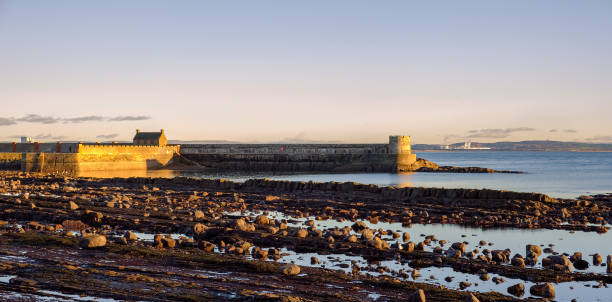 una baia rocciosa e un porto di salini in tarda serata - scenics coastline uk moss foto e immagini stock