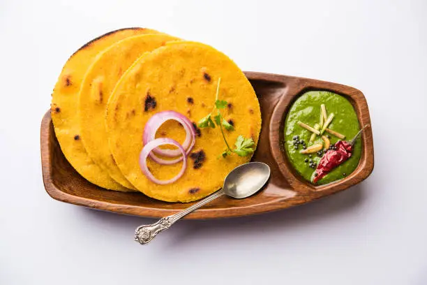 Photo of Makki di roti with sarson ka saag, popular punjabi main course recipe in winters made using corn breads mustard leaves curry. served over moody background. selective focus