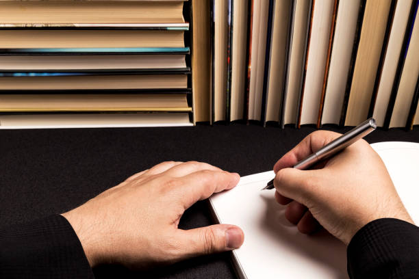 istock man writing in a blank book beside a book background 1077215100