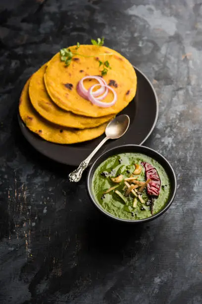 Photo of Makki di roti with sarson ka saag, popular punjabi main course recipe in winters made using corn breads mustard leaves curry. served over moody background. selective focus