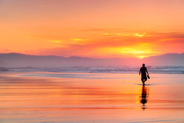 lonely person walking on beach at beautiful red sunset