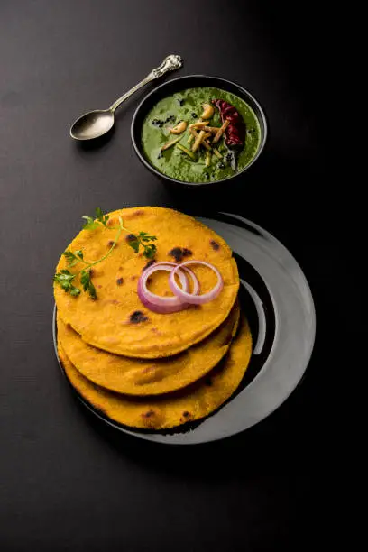 Photo of Makki di roti with sarson ka saag, popular punjabi main course recipe in winters made using corn breads mustard leaves curry. served over moody background. selective focus