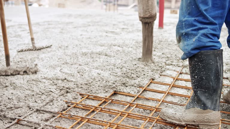 Construction workers pouring concrete across the wire mesh