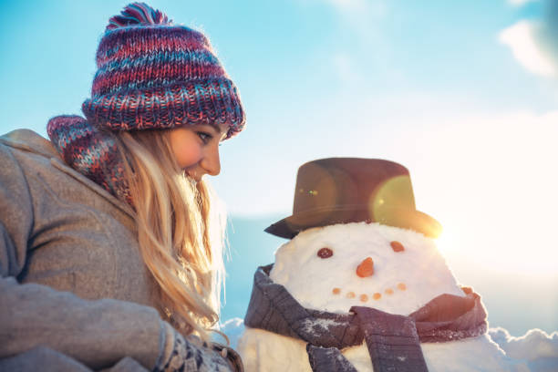 istock Happy nice female outdoors making a snowman 1077235190
