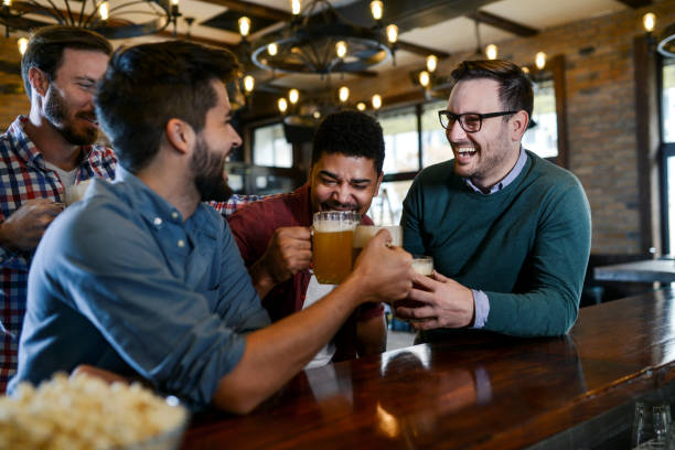 istock Group of young joyful friends having fun while toasting with beer in a pub 1077238988