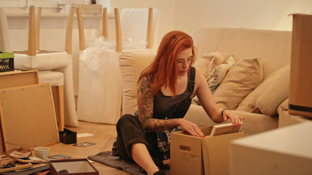 istock Single woman unpacking cardboard boxes in new apartment. 1077240786
