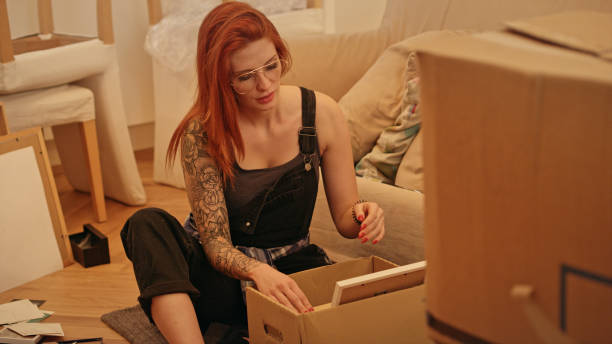 istock Single woman unpacking cardboard boxes in new apartment. 1077240794