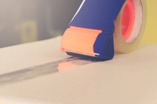 istock Preparing parcel for shipping with scissors and scotch tape cutter. 1077241892