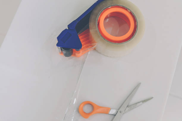 istock Preparing parcel for shipping with scissors and scotch tape cutter. 1077242054