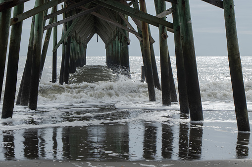 A rough day at the beach. Waves crashing in under a wooden pier