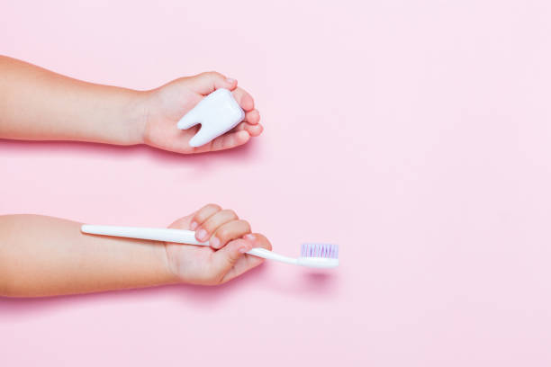 istock Child's hands holding big tooth and toothbrush 1077249868