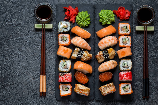 istock sushi rolls Asian food on rectangular shale plates with wasabi and ginger, soy sauce on dark background 1077252126
