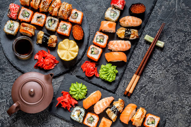 istock sushi rolls Asian food on rectangular shale plates with wasabi and ginger, soy sauce on dark background 1077252152