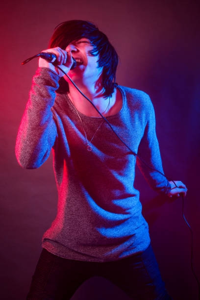 singing young guy The teenage boy or young singer guy is singing and screaming in microphone on the stage. emo boy stock pictures, royalty-free photos & images