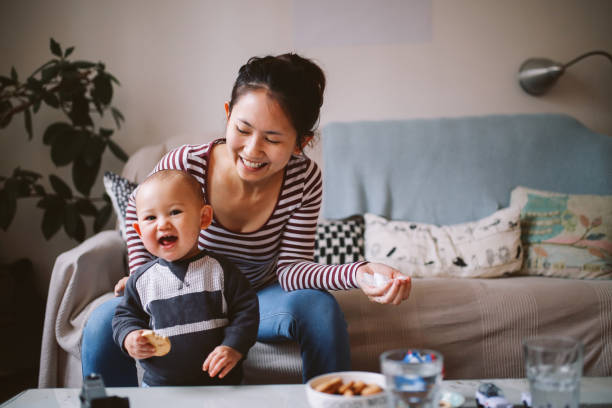 Young Asian mom playing with her baby boy at home Brightly lit image of a young Thai mom with her little baby boy. They're spending time together at home, playing with toys and having some snacks. Asian family lifestyle concepts, shot in Europe. expatriate photos stock pictures, royalty-free photos & images