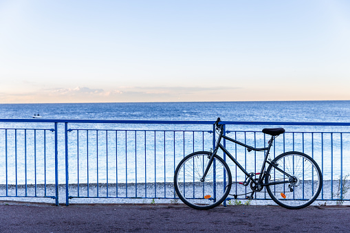 Nice, France - October 2, 2018: Silhouette scene of bicycle parking on fence beside Mediterranean sea at dawn of Nice, France.